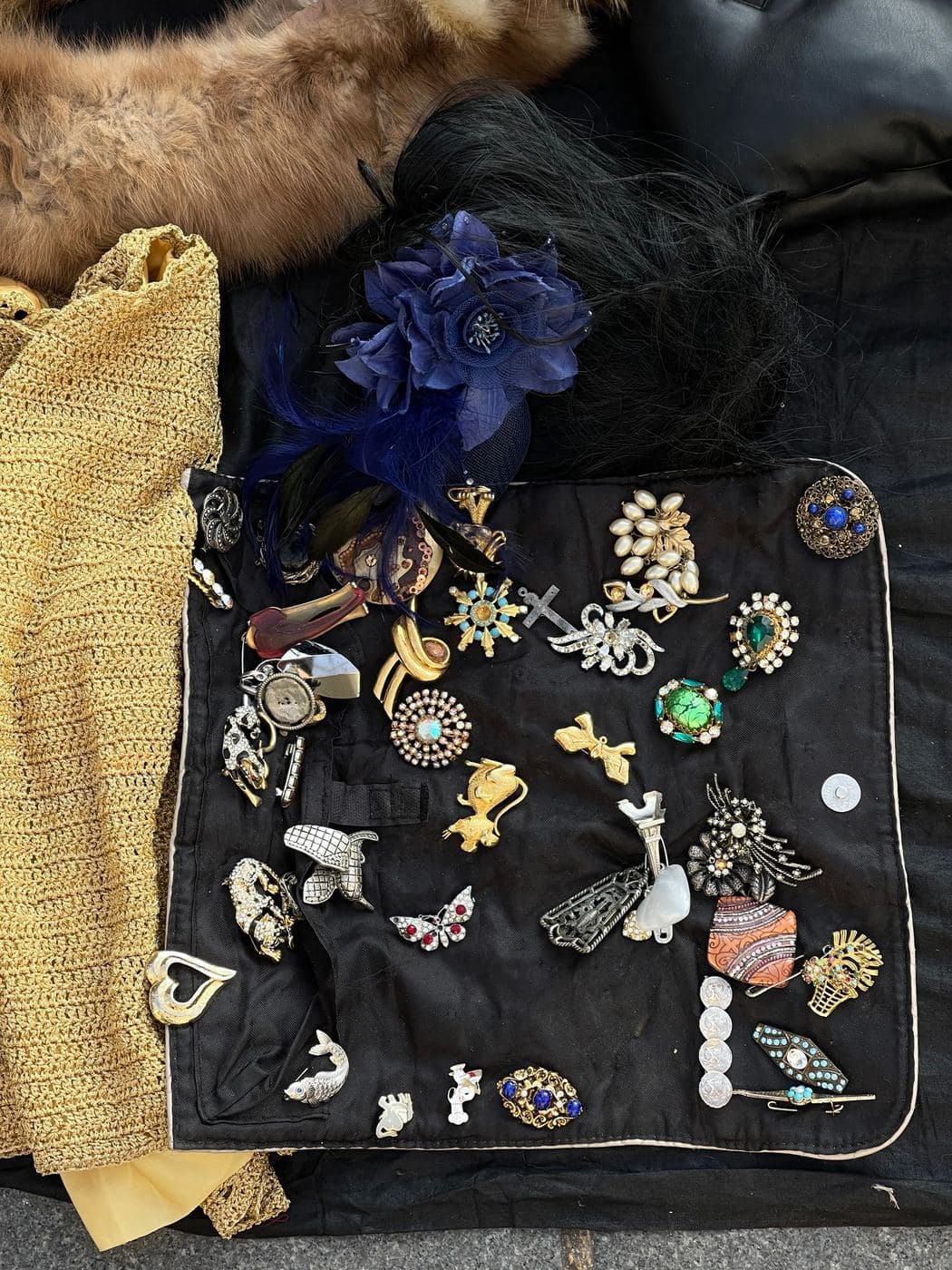 Black velvet board covered in assorted vintage brooches