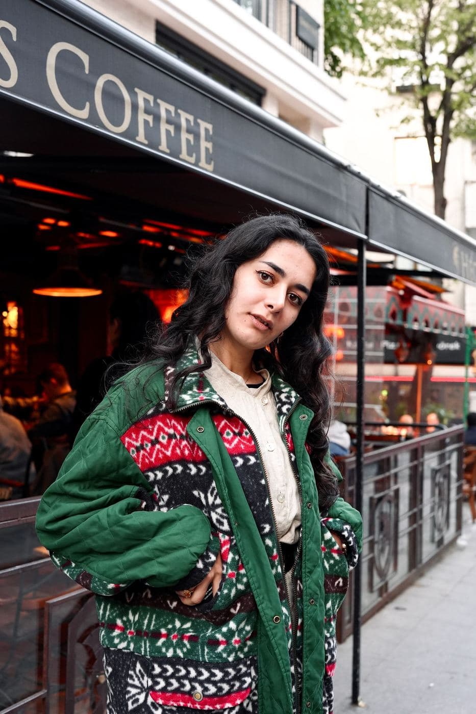 Woman outside a café in a green fleece jacket with a red and white Aztec pattern