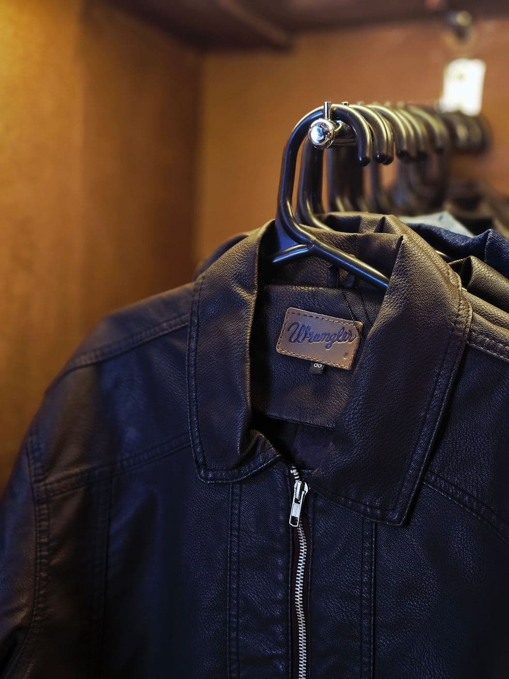 Navy zip-up Harrington jacket on a hanger in a dark wardrobe
