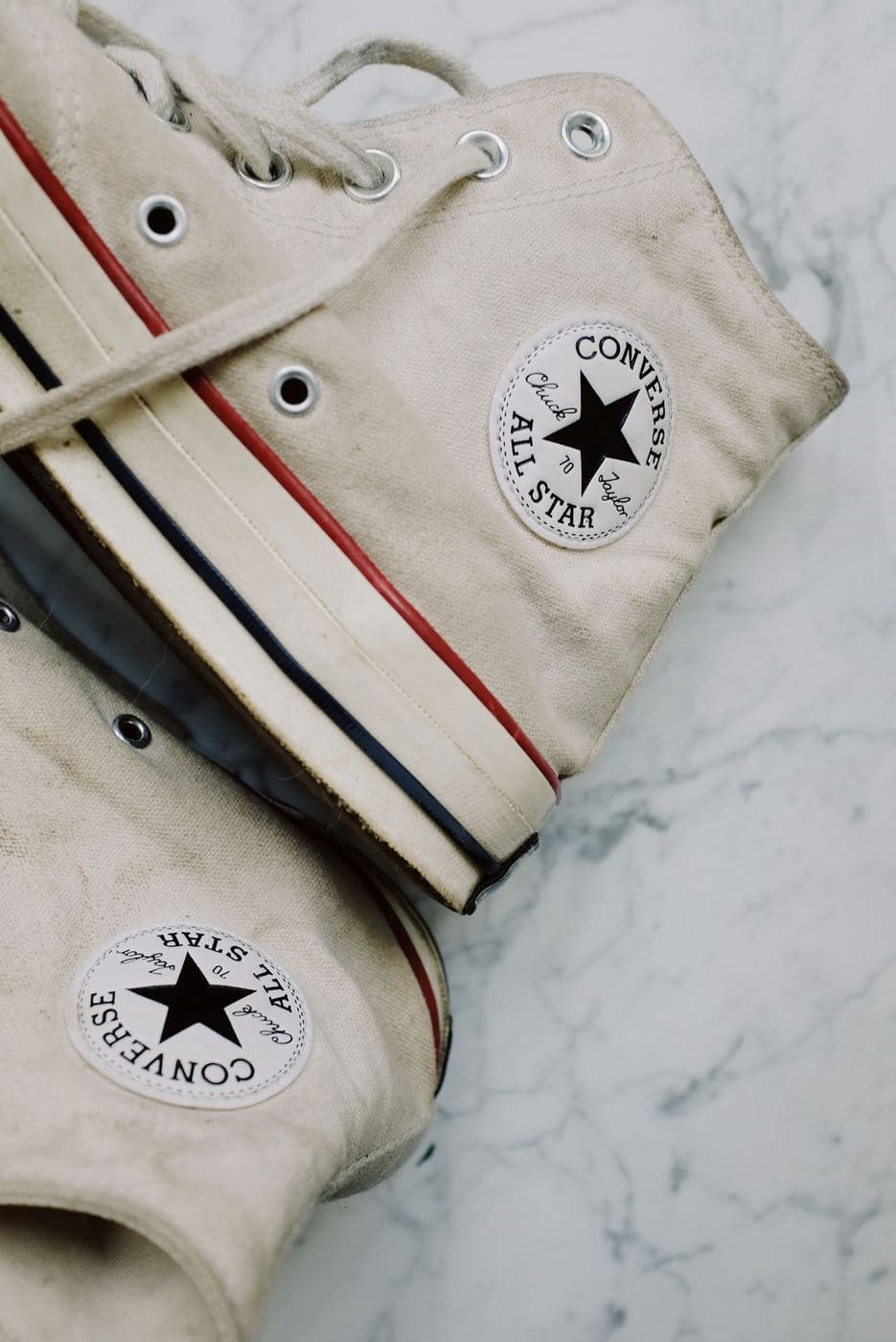 Cream canvas high-top trainers on a marble surface