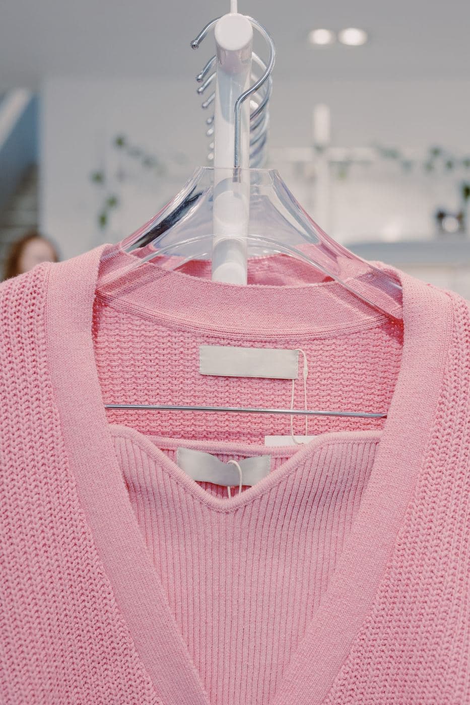 Pink fine-knit V-neck top on a clear plastic hanger