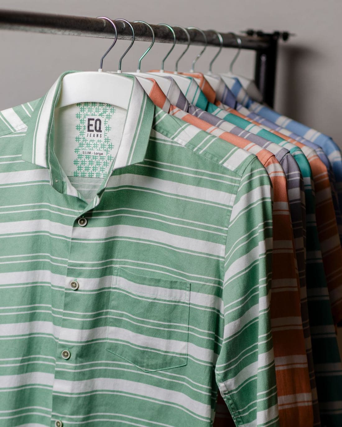 Green and white striped short-sleeved shirt on a rail of patterned shirts