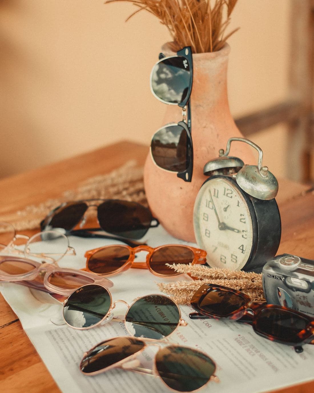 Assorted vintage sunglasses laid out next to an alarm clock