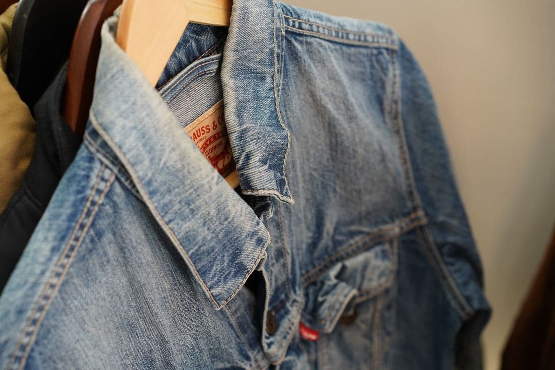 Close-up of a stonewash blue denim trucker jacket on a hanger