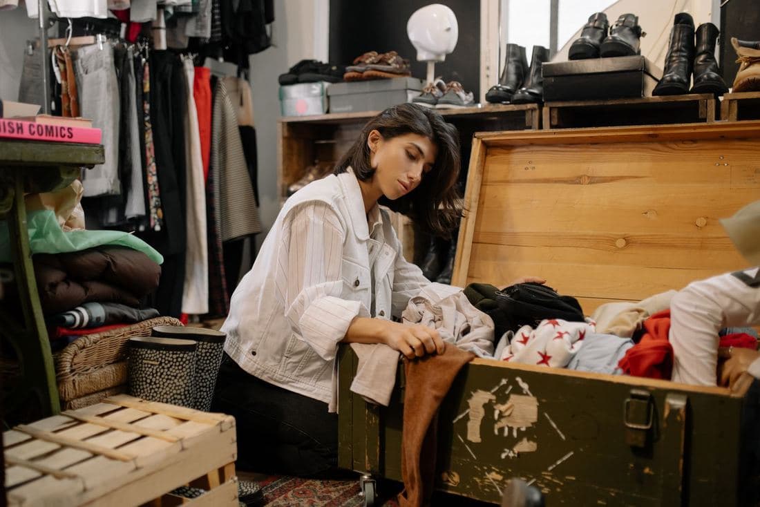 A woman sitting on the floor sorting through a box of clothes