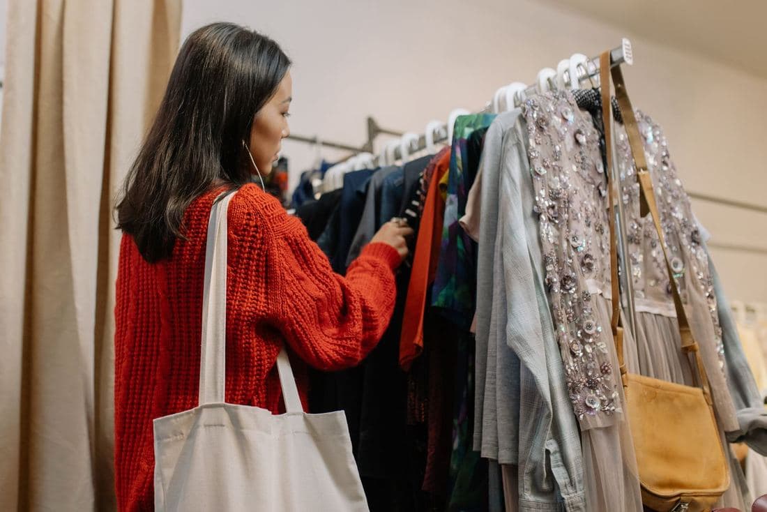 A woman in a red jumper browsing a rail of clothes