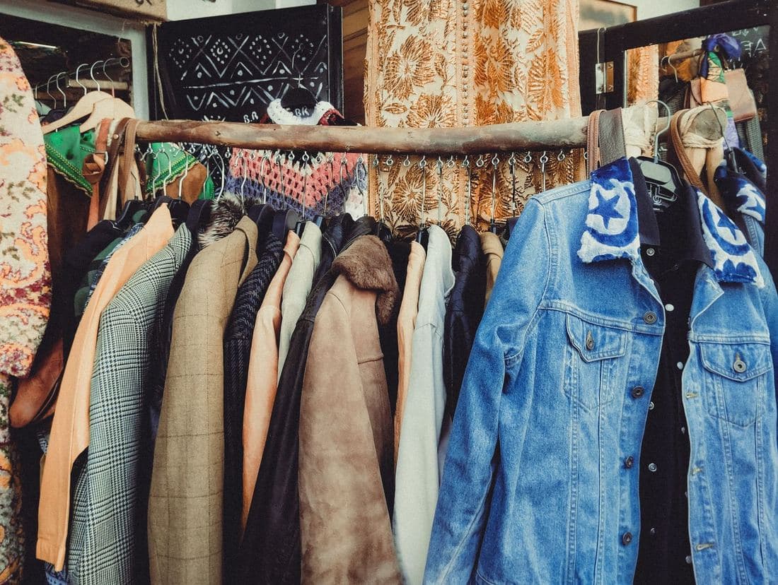 A wooden rail of bright vintage jackets