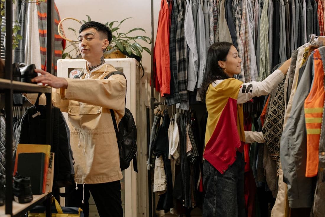 Two shoppers browsing packed rails of colourful vintage clothes